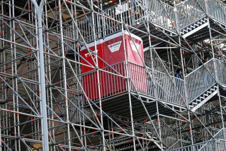 Gerüst mit rotem Bauaufzug, der Material nach oben bringt