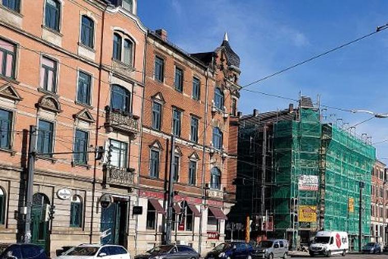 Eingerüstetes Eckhaus an einer Straße, Gerüst reicht bis über den Gehsteig