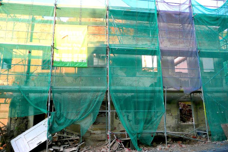 Gerüst mit grünem Schutznetz vor einer Fassade