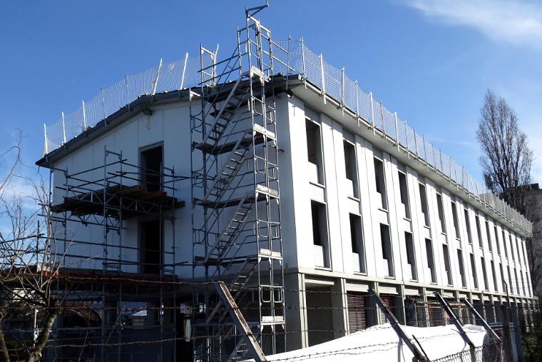 Großes Gebäude mit Gerüst und Treppenaufgang über mehrere Geschoße